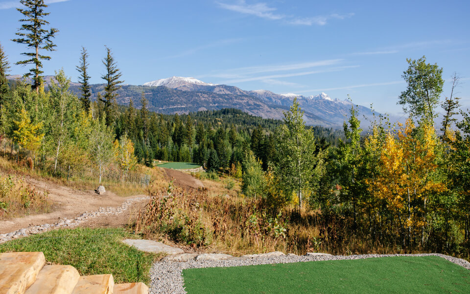 greens visible amid rough natural landscape with mountain peaks in the distant background